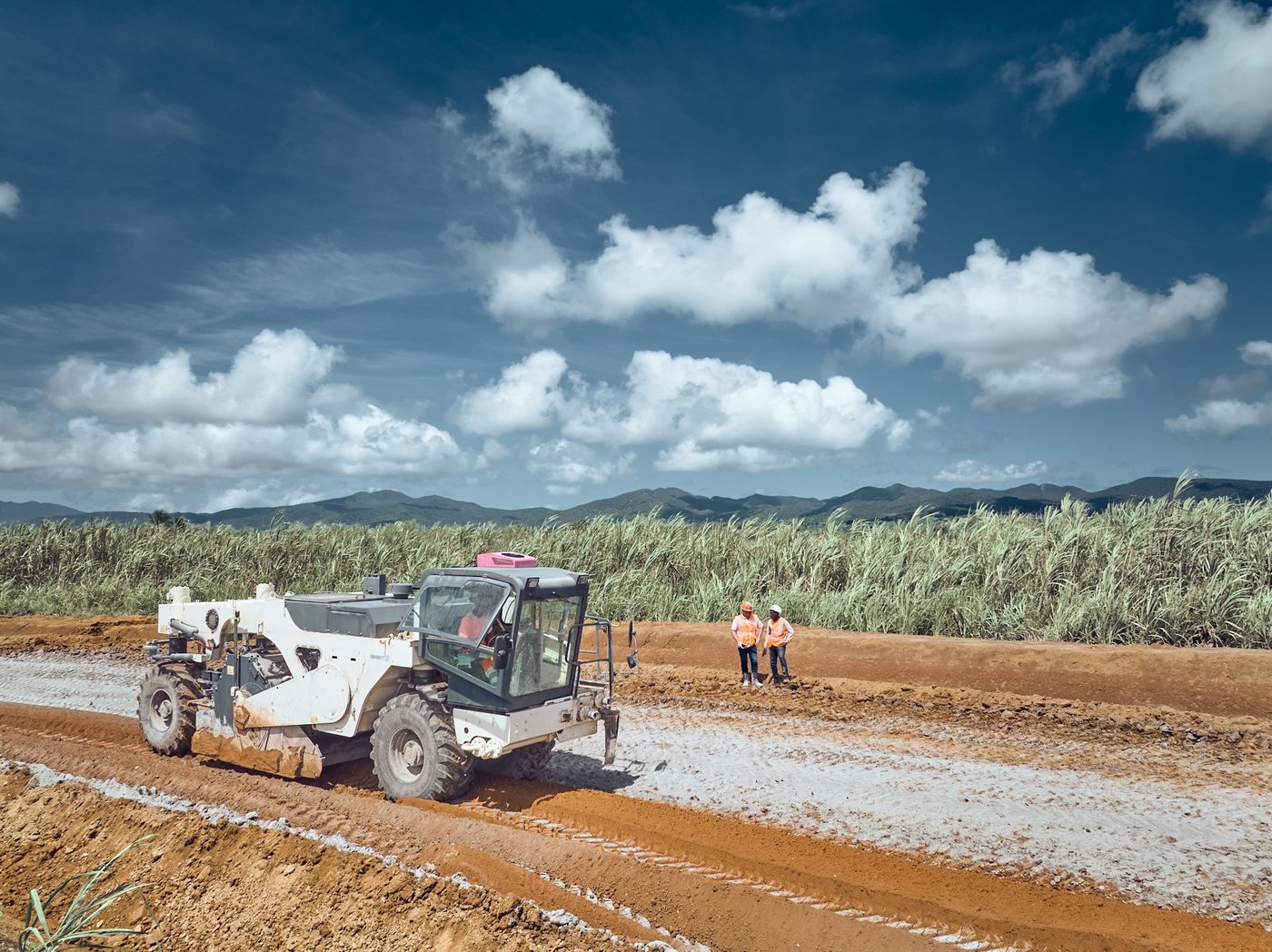 Engin de terrassement sur un chantier routier entre les champs de canne — photographie Romain Cruse