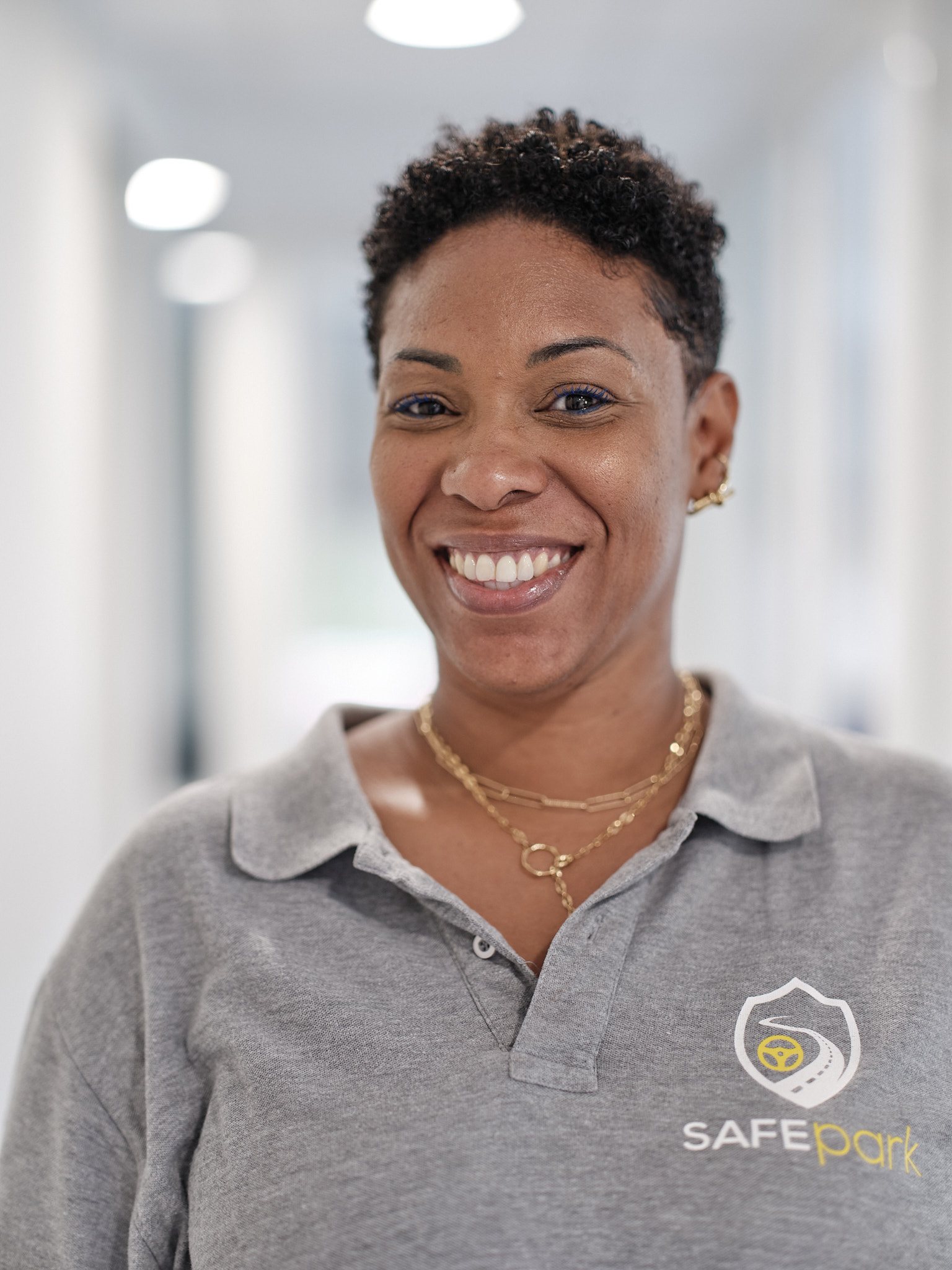 Portrait corporate — collaboratrice souriante en polo d'entreprise dans un couloir de bureaux — photographie Romain Cruse