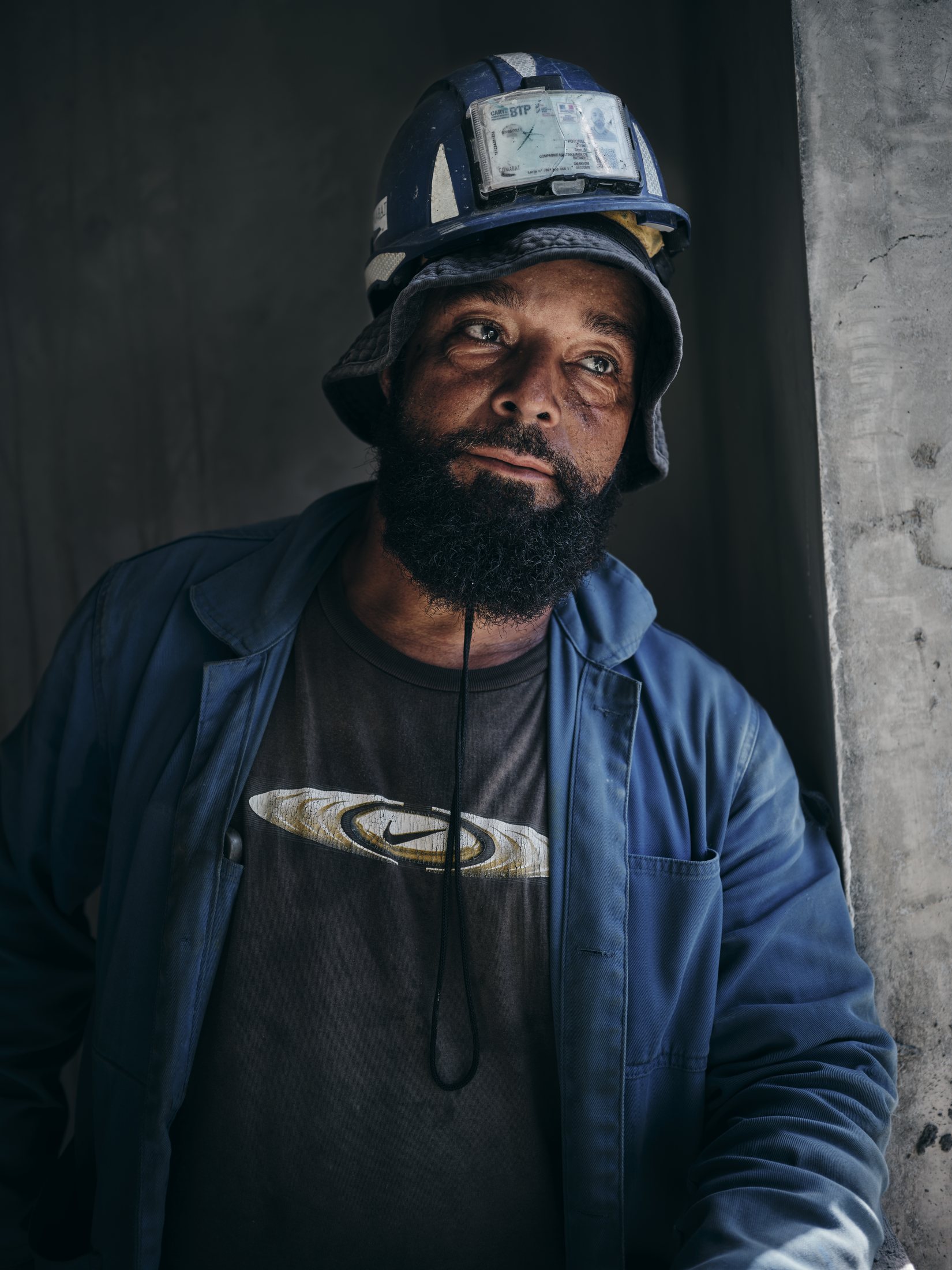 Portrait de métier — ouvrier casqué, regard droit, fond sombre d'atelier — photographie Romain Cruse
