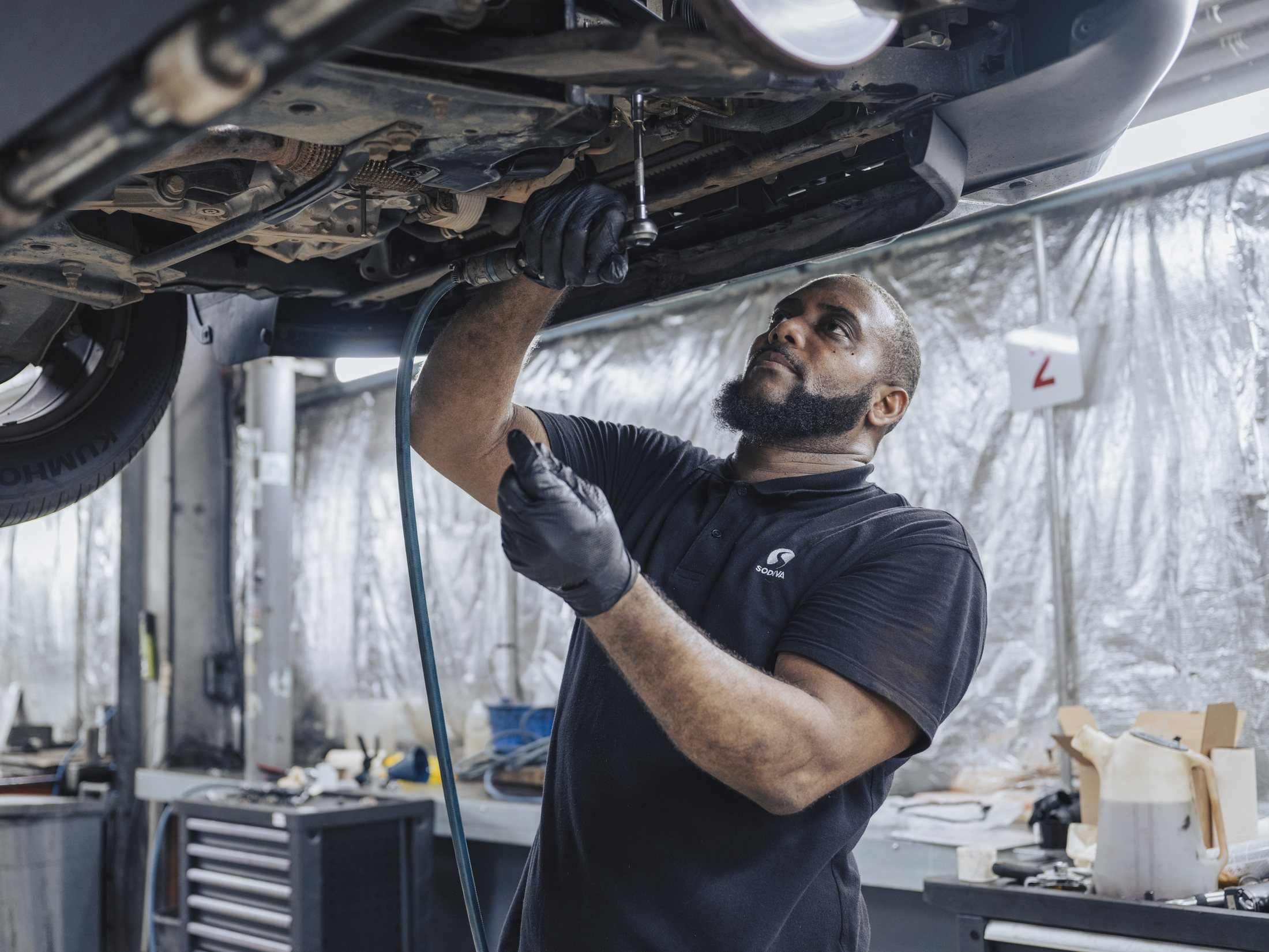 Portrait de métier — mécanicien au travail sous un pont élévateur, atelier automobile, Martinique — photographie Romain Cruse