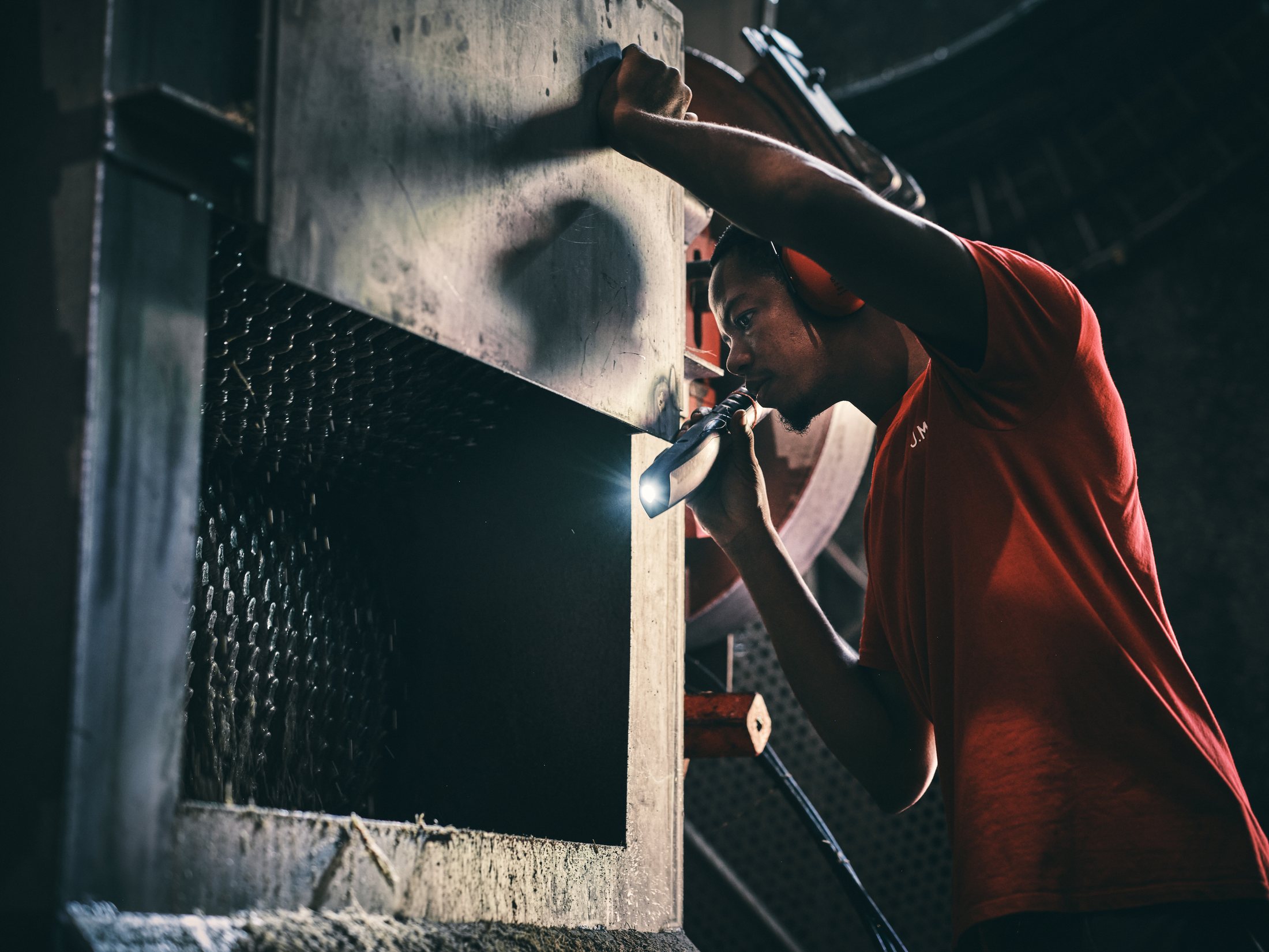 Portrait de métier — technicien en combinaison rouge au travail sur une installation industrielle — photographie Romain Cruse