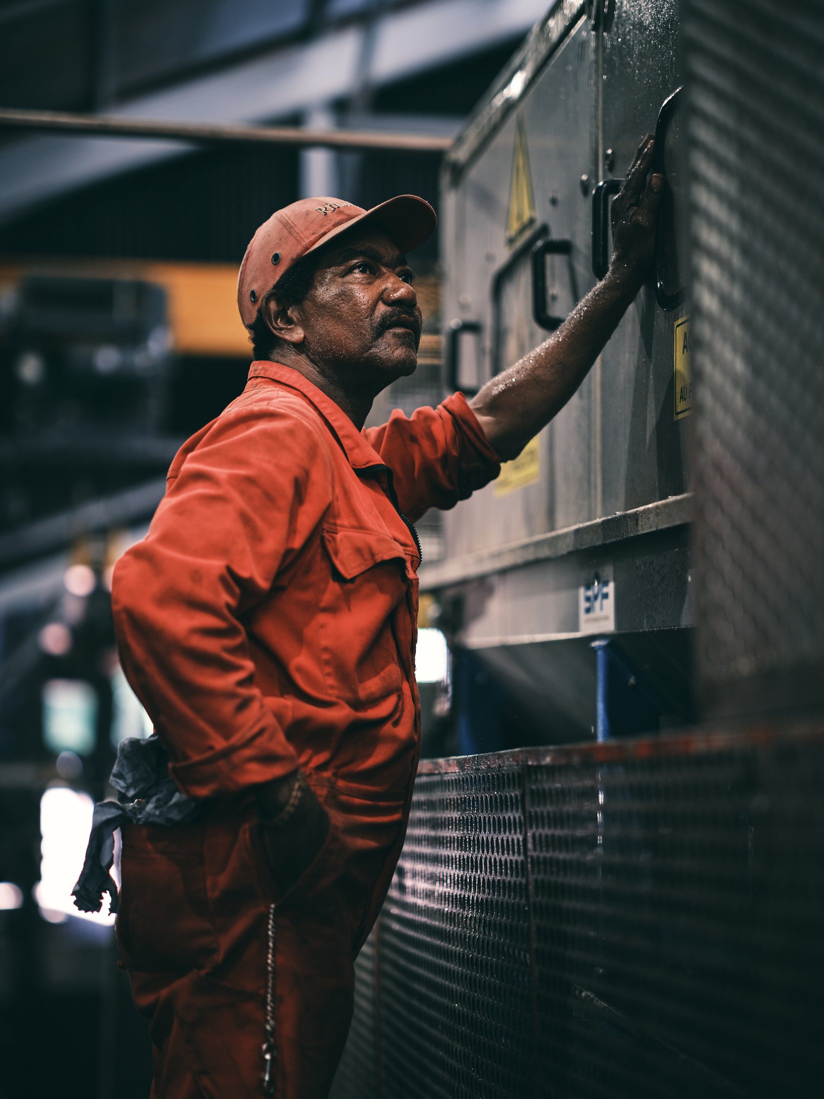 Portrait de métier — technicien en combinaison rouge, debout, regard vers l'objectif — photographie Romain Cruse